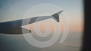 View from the plane. Airplane window. Flying plane in the sky at sunset. Pastel background. Travel concept.