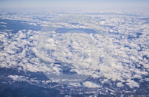 View from a plane window on clouds and blue clear sky and the earth from height. Beautiful view from air of mountains.