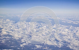 View from a plane window on clouds and blue clear sky and the earth from height. Beautiful view from air of mountains.