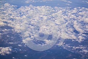 View from a plane window on clouds and blue clear sky and the earth from height. Beautiful view from air of mountains.