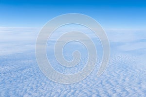 The view from the plane window of dense curly clouds and the blue stratosphere. Cloudscape. Blue sky and white cloud