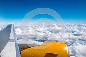 View from the plane window: flying above the clouds. Clear blue skies, fluffy cirrus clouds. Horizontal photo. Travel and tourism