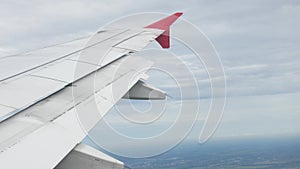 view through plane window from inside airplane cabin while climbing flying over the sky with airplane wing winglet and fluffy