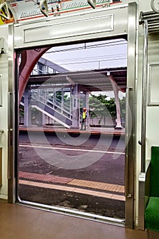 View of platform through open sliding doors from inside of an empty commuter train car stopped at Railway Station