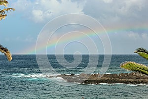 View of the Playa de la Arena and rainbow over the sea, the phenomenon of nature, bright colors on the rainbow and cloudy sky