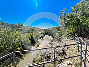 View point with metal bar barrier looking down Honey Creek where it tumbled over Bridal Veil Falls upstream of Turner Falls with