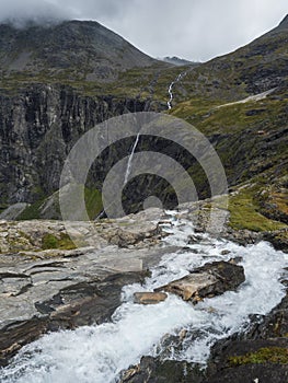 View point platform on Trollstigen or Trolls Path with green valley and waterfall at massif Trolltindene in Romsdal valley, Norway