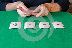 View of poker aces on green mat with woman`s hands that are going to hand out cards