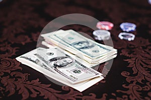 View of poker table with pack of cards, tokens, alcohol drinks, dollar money and group of gambling rich wealthy people playing