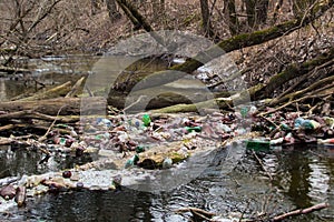 View of the polluted small forest river with a lot of different plastic garbage. Environment pollution problem