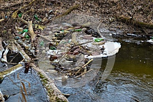 View of the polluted small forest river with a lot of different plastic garbage. Environment pollution problem