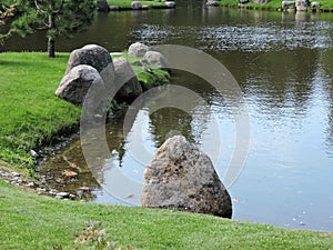View of  pond  with green coasts, big stones and pine  in the park, Tallinn