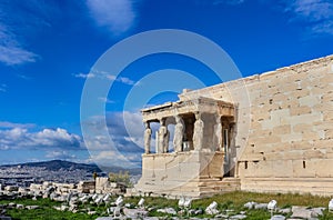 View of the Porch of the Caryatids on the Erechtheion temple on the Athens Accropolis with a view of Athens and a mountains in the