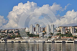 View of the port in Croatia, the city of Rijeka, blocks by the sea, high blocks, built-up coast, white thick clouds, cranes in the