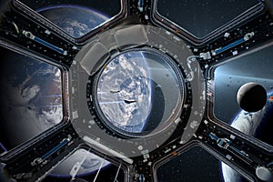 View from a porthole of space station on the Earth background.