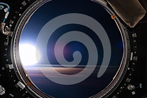 View from a porthole of space station on the Earth background.