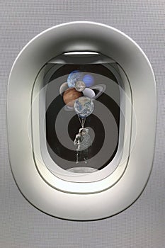 View from porthole window on astronaut with planets shaped balloons in solar system. Elements of this image furnished by NASA