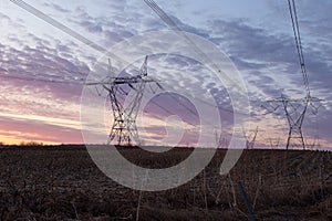 View of power line towers in farmland fields during a beautiful spring sunrise, St.-Pierre, Island of Orleans