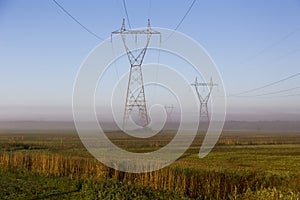 View of power line towers in fields during a beautiful misty late summer golden hour morning