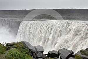 View of the powerfull Detifoss waterfall with grass and rocks on