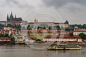 View of Prague Castle and a boat on the Vltava river on a rainy