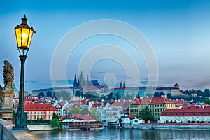 View of Prague Castle, mala Strana and Vltava river in Prague from Charles Bridge with street lamp during blue hour sunrise