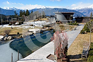 A view of a prestigious hotel near a small lake and scenery against the background of distant snowy mountains