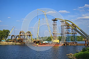 View the process of mounting steel structures for construction of a new pedestrian bridge over river.