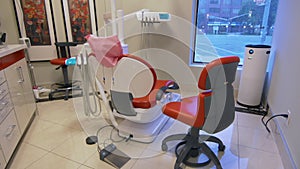 View of professional dentist room with red chairs and other stomatological equipment.