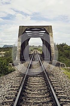 View of railway and old steel bridge with green tree at the left and right side of railway,blue sky and clouds on background