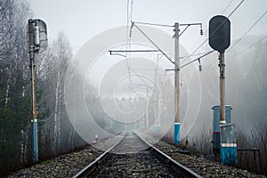 View of railway, traffic lights and electric poles in fog in spring