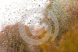 View of Rain drops on window with green,red and yellow color tree in background Autumn Abstract blurred Backdrop