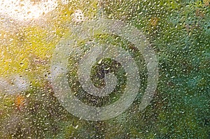 View of Rain drops on window with green,red and yellow color tree in background Autumn Abstract blurred Backdrop