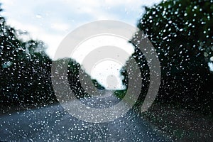 A view of the rainy weather through the windshield of a car that rides along the road.