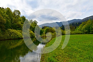 View of Rak river and grassy plains next to it with Javorniki mountains