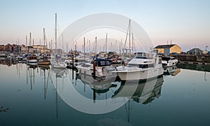 View of Ramsgate Royal Harbour taken in the early evening light, with the masts of the yachts reflected in the water.
