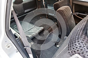 A view through the rear passenger seats inside the cabin of a Japanese station wagon to the roomy trunk with a black rubber mat