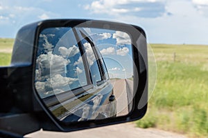 View into the rear-view mirror on a lonely country road, Wyoming