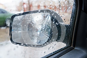 View of the rear view mirror on a rainy day from inside the car