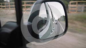 view from rear-view mirror, roadway with cars is reflected in mirror while driving around city, close-up