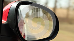 View in the rear view side mirror of a auto, driving a red car along the track