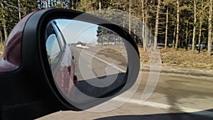 View in the rear view side mirror of a auto, driving a red car along the track