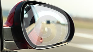 View in the rear view side mirror of a auto, driving a red car along the track