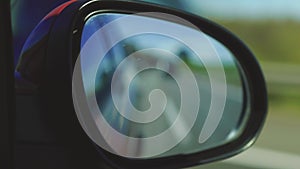 View in the rear view side mirror of a auto, driving a red car along the track