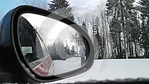 View in the rear view side mirror of a auto, driving a red car along the track