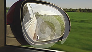 View in the rear view side mirror of a auto, driving a red car along the track