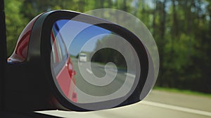 View in the rear view side mirror of a auto, driving a red car along the track