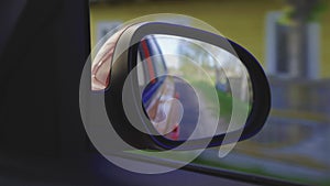 View in the rear view side mirror of a auto, driving a red car along the track