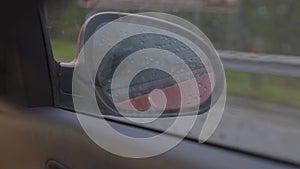 View in the rear view side mirror of a auto, driving a red car along the track