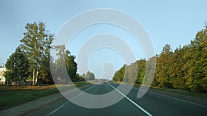 View through rear windshield windscreen of car in motion, back glass screen. Single carriageway with two-lane road along